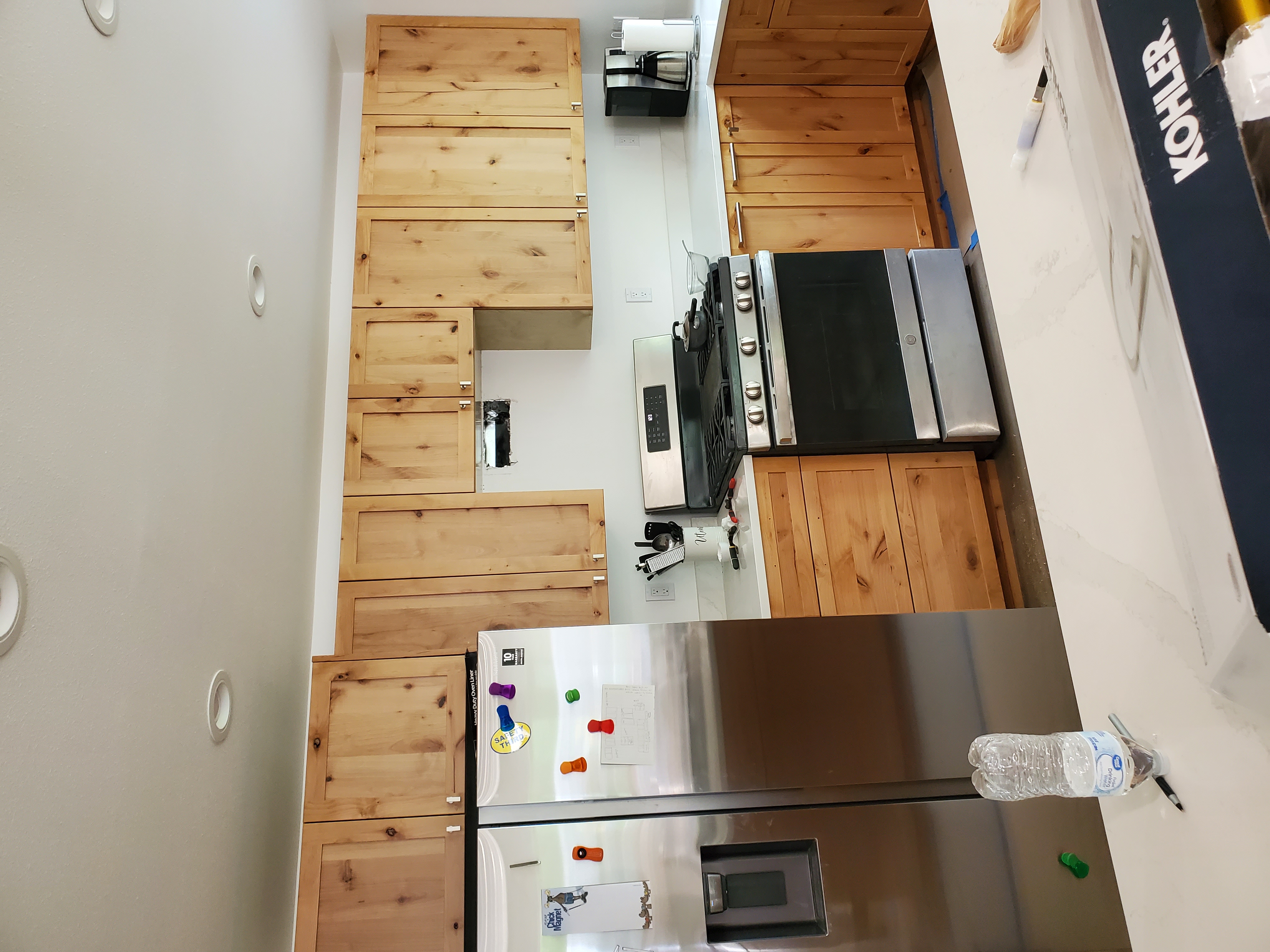 Sawbox custom knotty wood kitchen cabinets installed around a range and refrigerator.