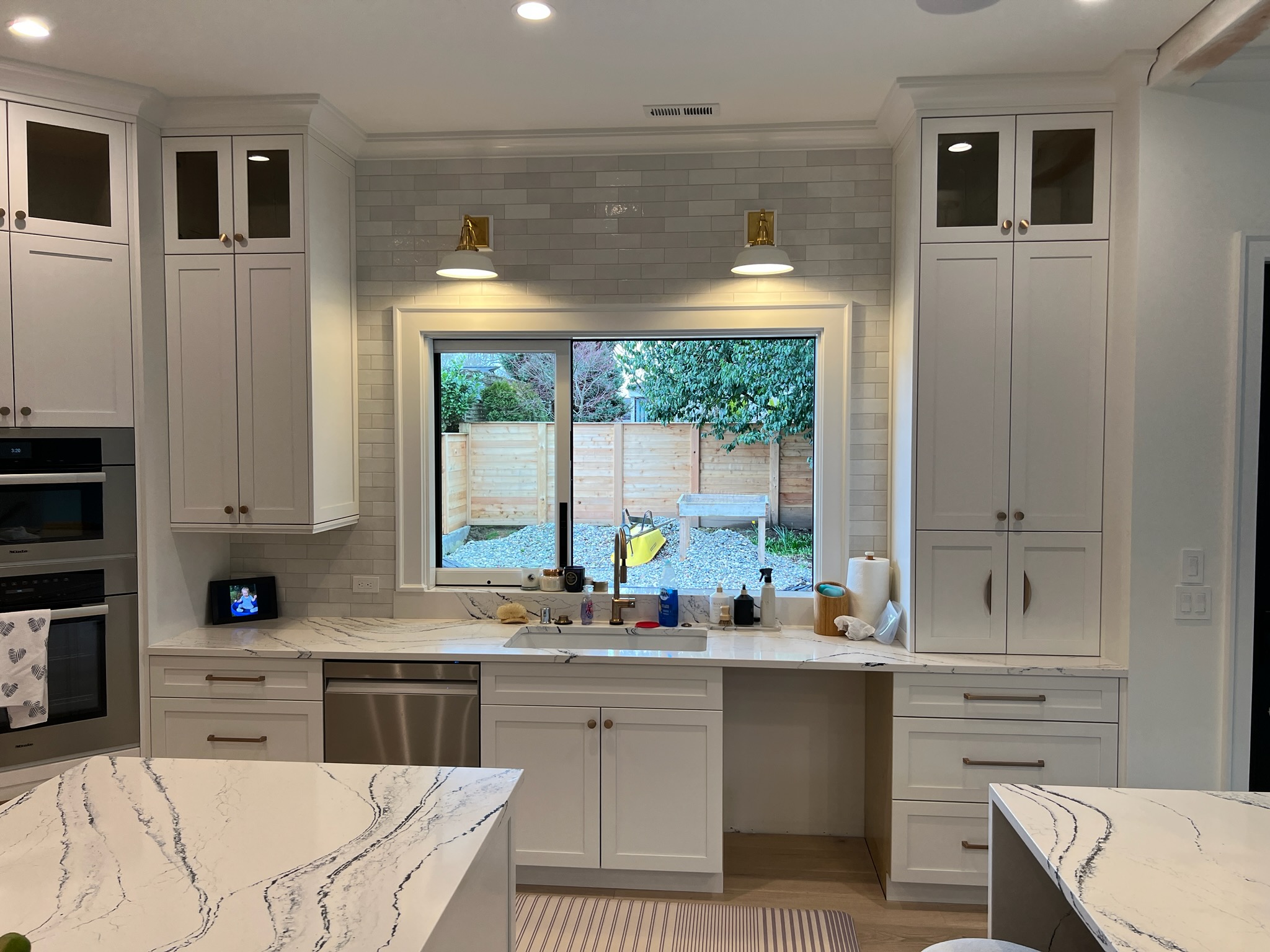 White shaker kitchen with dark island and tall pantry cabinets.